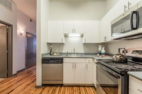 Plano apartment for rent - a kitchen with white cabinets and stainless steel appliances and a stove