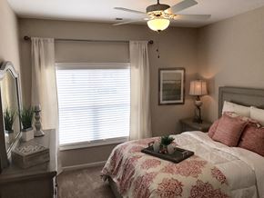 Garner apartment for rent - a bedroom with a bed and a ceiling fan and a window