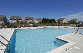 Garner apartment for rent - a resort style pool with chairs and umbrellas and houses in the background