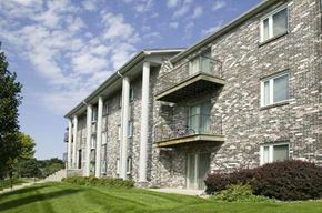 Omaha apartment for rent - a brick apartment building with balconies and a green lawn