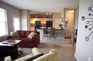 Omaha apartment for rent - A living room with a red couch and a white wall with a decoration on it.