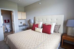 Omaha apartment for rent - A bed with a white headboard and red and black pillows in a bedroom.