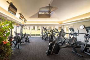 Omaha apartment for rent - a gym with cardio machines and a window overlooking the grass