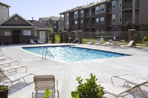 Council Bluffs apartment for rent - A pool surrounded by chairs and apartment buildings.