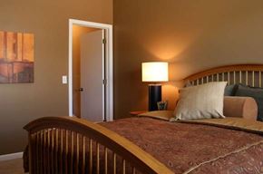 Council Bluffs apartment for rent - A bedroom with a bed, lamp, and painting.