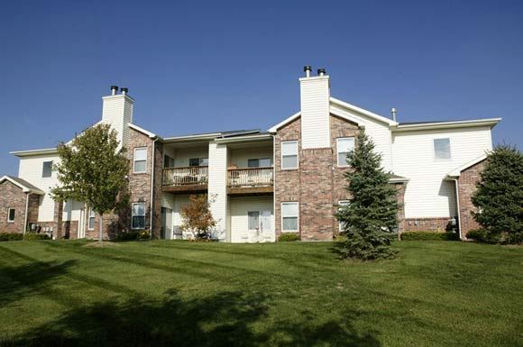 Omaha apartment for rent - an apartment building with green grass and trees