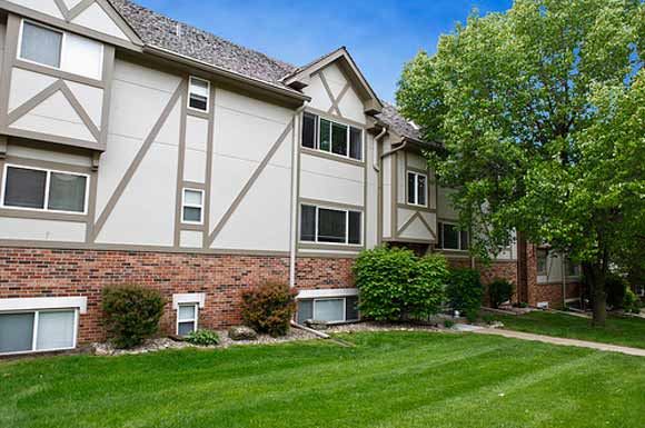 Omaha apartment for rent - an apartment building with a green lawn and trees