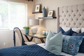 Omaha apartment for rent - a bedroom with a bed with blue pillows and a desk with a lamp