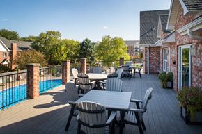 Omaha apartment for rent - A patio with a table and chairs overlooking a pool.