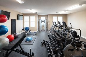 West Des Moines apartment for rent - a gym with cardio equipment and weights on the floor