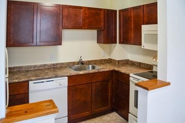 Lowell apartment for rent - A kitchen with brown cabinets and a white dishwasher.