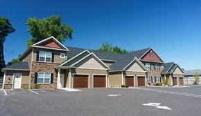 Latham apartment for rent - A large, multi-family home with a parking lot in front.
