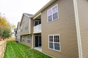 Latham apartment for rent - A residential building with a brown siding and a green lawn in front.