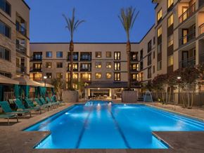 Phoenix apartment for rent - A large swimming pool in front of a building with palm trees.