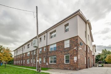 Oshawa apartment for rent - A large brick building with a grey roof and multiple windows.