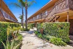 Downey apartment for rent - the walkway through the courtyard of a building with palm trees