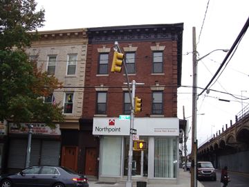 Ozone Park apartment for rent - an old brick building on a street corner with a traffic light
