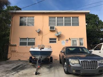 West Palm Beach apartment for rent - A car is parked in front of a pink house.
