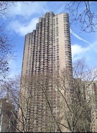 New York apartment for rent - A tall building with many windows is surrounded by trees.