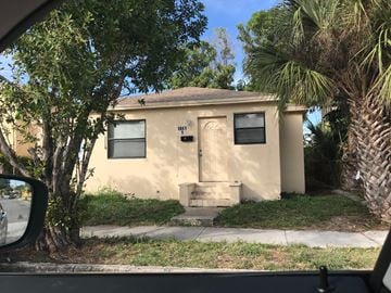 West Palm Beach apartment for rent - A small beige house with a black door and windows.