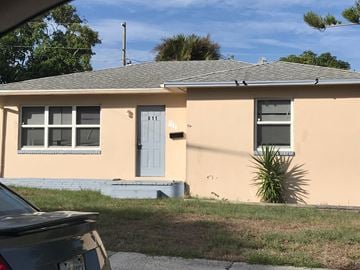 West Palm Beach apartment for rent - a yellow house with a blue door and a car parked in front