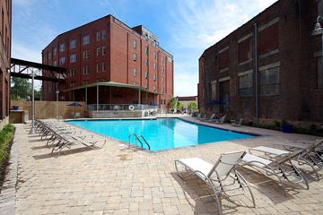 Richmond apartment for rent - A pool surrounded by chairs in front of a brick building.