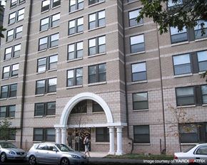 Washington apartment for rent - A large building with a white archway entrance and cars parked in front.