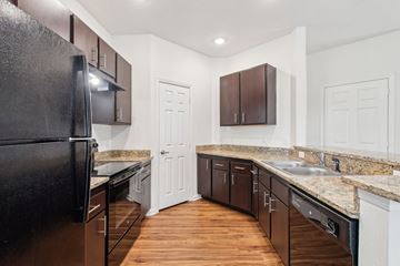 Jacksonville apartment for rent - A kitchen with a black refrigerator and brown cabinets.