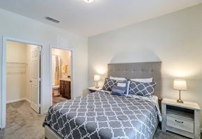 Jacksonville apartment for rent - A bedroom with a large bed and a nightstand with a lamp.