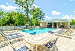 Jacksonville apartment for rent - A pool surrounded by lounge chairs and a building in the background.