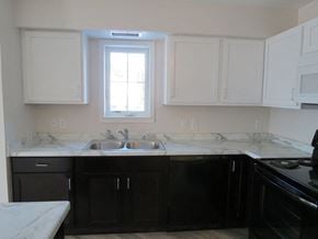 Cambridge apartment for rent - a kitchen with white marble counter tops and black appliances