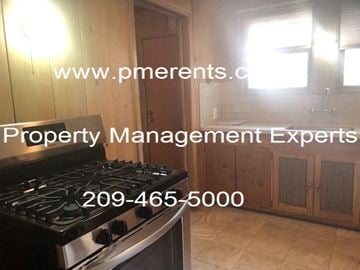 Stockton apartment for rent - A kitchen with a stove and a website address for property management experts.