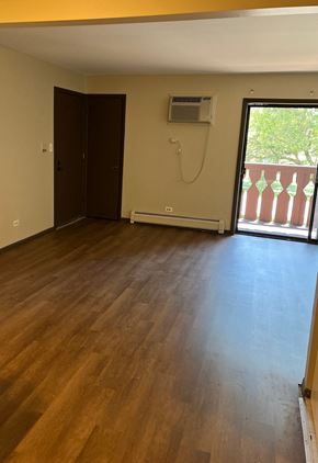 Oak Forest apartment for rent - A room with wooden floors and a balcony with a view of trees.
