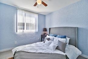 Phoenix apartment for rent - the master bedroom has a large bed and a ceiling fan