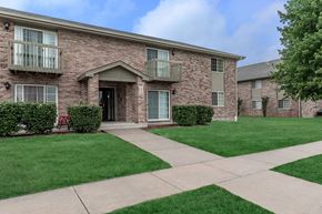 Dekalb apartment for rent - A brick building with a green lawn in front.