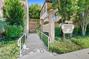 Bellflower apartment for rent - a sidewalk in front of a building with a staircase and a gate