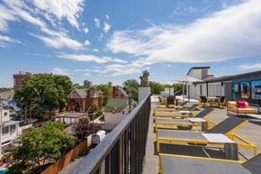 Denver apartment for rent - a rooftop patio with yellow tables and chairs and buildings in the background