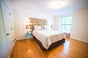 Kansas City apartment for rent - A bedroom with a bed, wooden headboard, and a blue stool.