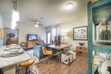 Fort Worth apartment for rent - A living room with a TV, a table, chairs and a painting on the wall.