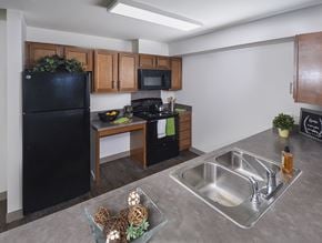 Columbus apartment for rent - A kitchen with a black fridge, microwave, and stove top oven.