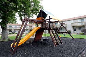 Stow apartment for rent - a swing set in a playground in front of an apartment building