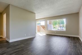 Oceanside apartment for rent - A spacious room with wooden flooring and a view of a street through the window.