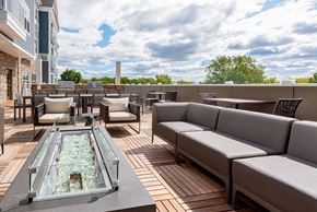 River Edge apartment for rent - a rooftop patio with couches and tables and a glass fireplace