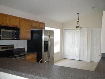 Jacksonville house for rent - A kitchen with a black refrigerator and wooden cabinets.