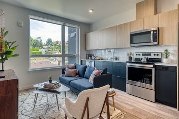 Seattle apartment for rent - a living room with a blue couch and a kitchen with stainless steel appliances