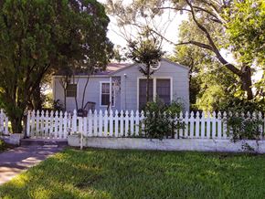 Tampa house for rent - A house with a white picket fence is surrounded by trees.