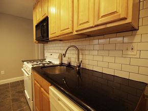 Philadelphia house for rent - A kitchen with a black countertop and white tiled backsplash.