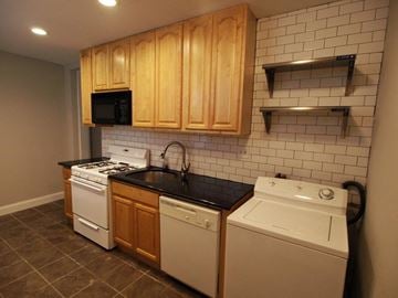Philadelphia house for rent - A kitchen with a white dishwasher and a black countertop.