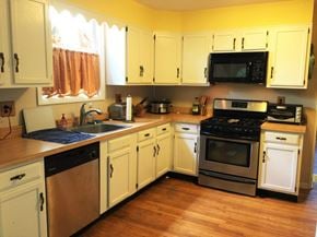 Philadelphia house for rent - A kitchen with white cabinets and a black microwave above the stove.