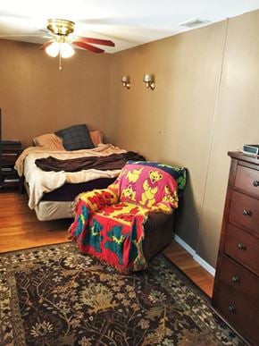 Philadelphia house for rent - A bedroom with a bed and a chair covered in a colorful blanket.